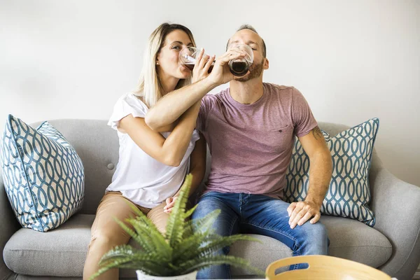 Relajada pareja joven viendo la televisión y bebiendo cerveza en casa — Foto de Stock