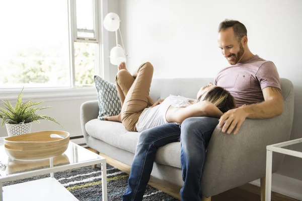 Pareja joven tumbada en el sofá relajándose en casa — Foto de Stock