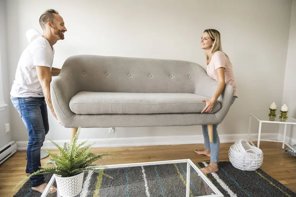 Longitud completa de la pareja feliz colocación de sofá en la sala de estar de nuevo hogar — Foto de Stock