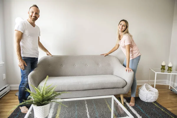 Longitud completa de la pareja feliz colocación de sofá en la sala de estar de nuevo hogar — Foto de Stock