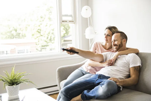 Couple watching tv at home sitting in a comfortable couch in the livingroom at home — Stock Photo, Image