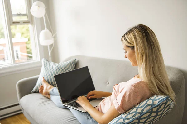 Vrouw met een laptop op de Bank thuis — Stockfoto