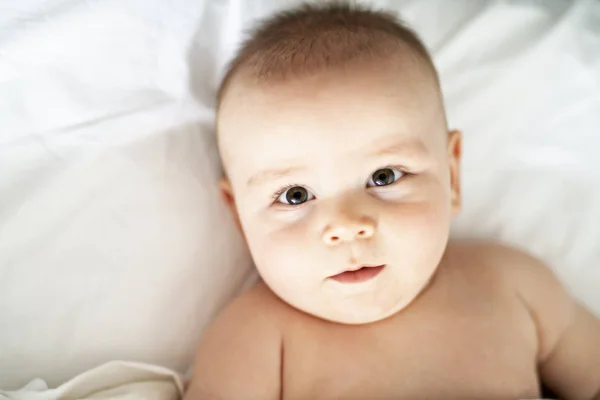 快乐逗人喜爱的婴孩躺在白色床单 — 图库照片