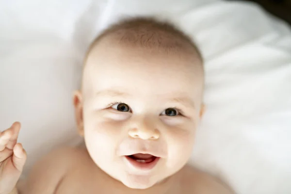 Glückliches süßes Baby liegt auf weißem Laken — Stockfoto