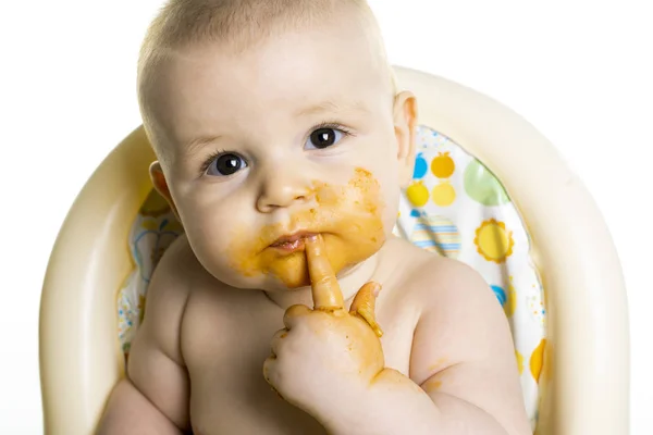 Piccolo bambino mangiare la sua cena spaghetti e fare un pasticcio sul suo viso — Foto Stock