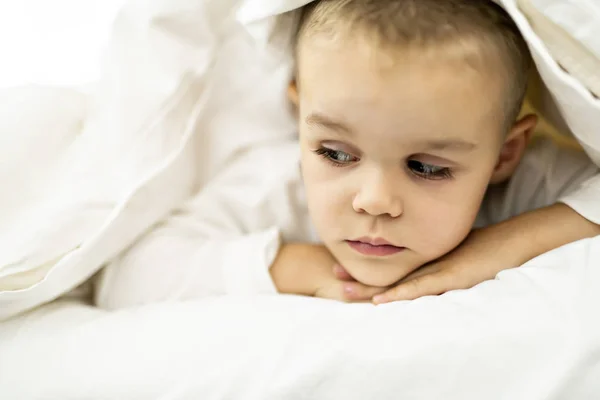 Carino quattro anni ragazzo in bianco biancheria da letto — Foto Stock