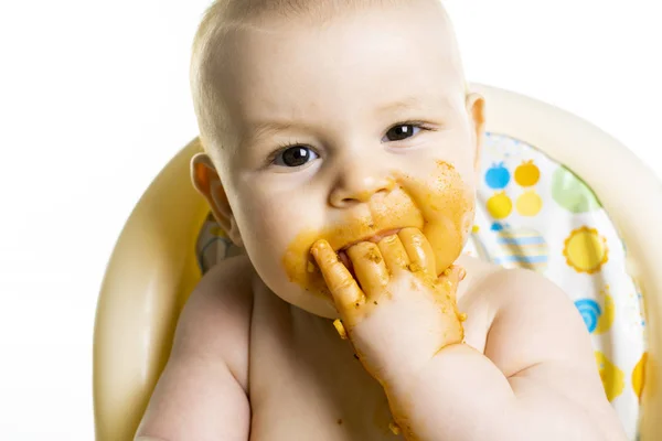 Lilla bebis äta hennes middag spaghetti och göra en röra på hans ansikte — Stockfoto