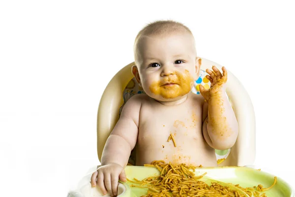 Pequeño bebé comiendo sus espaguetis de cena y haciendo un lío en su cara — Foto de Stock