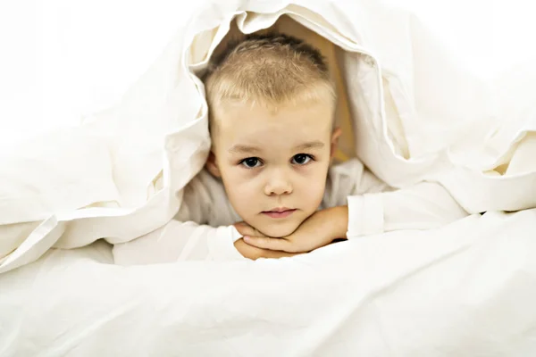 Bonito quatro anos menino no branco cama — Fotografia de Stock