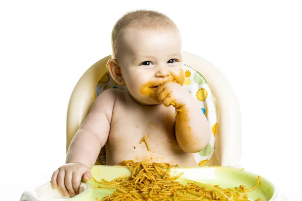 Pequeño bebé comiendo sus espaguetis de cena y haciendo un lío en su cara — Foto de Stock