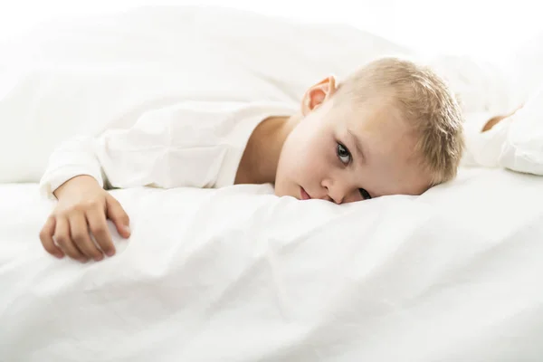 Carino quattro anni ragazzo in bianco biancheria da letto — Foto Stock
