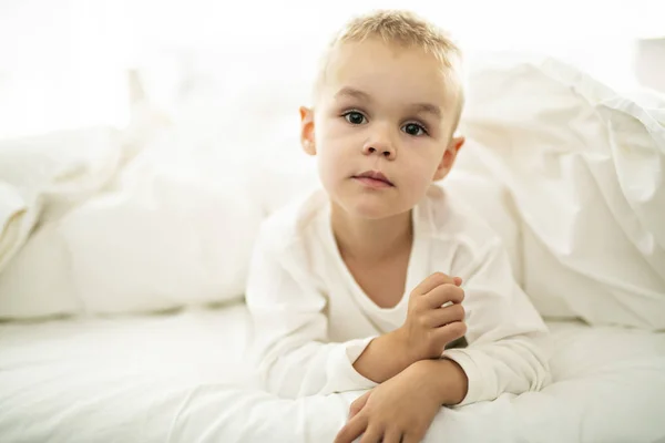 Bonito quatro anos menino no branco cama — Fotografia de Stock
