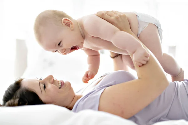 Mother lay on bed with his baby — Stock Photo, Image