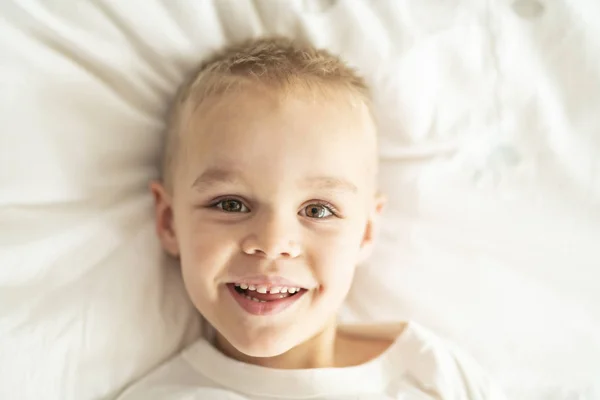 Schattig vier jaar jongen in wit beddengoed — Stockfoto