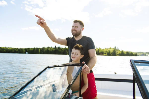 Man driving boat on holiday with his son kid