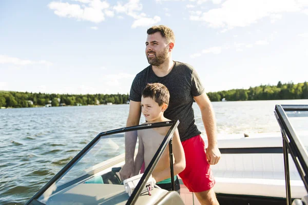 Man driving boat on holiday with his son kid