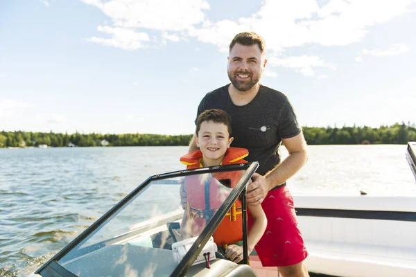 Man driving boat on holiday with his son kid