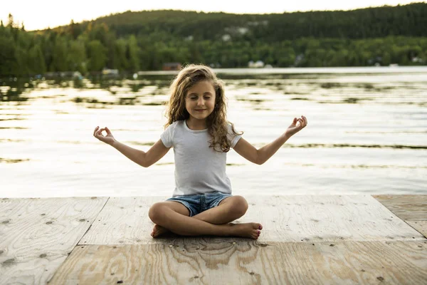 Dítě dívka jóga relaxovat v molu v západu slunce — Stock fotografie