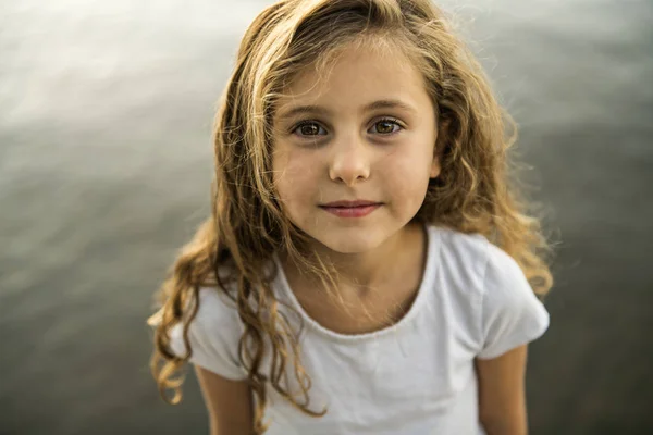 Linda niña en una plataforma de madera junto al lago . —  Fotos de Stock