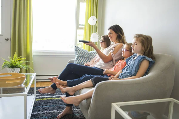 Mãe e filhas no sofá em casa ouvindo TV — Fotografia de Stock