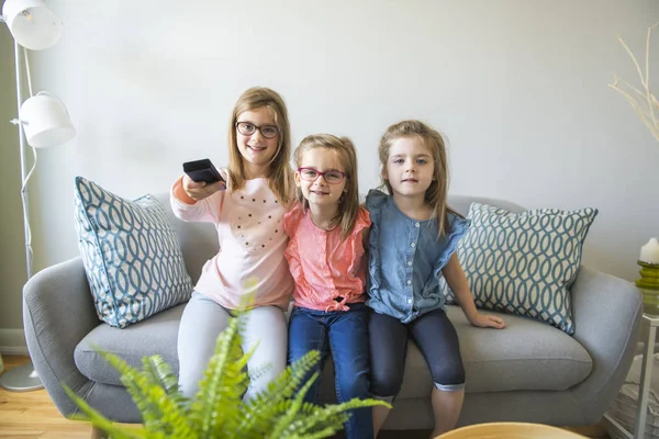 Τρεις αδερφές κορίτσια κάθονται στον καναπέ στο σπίτι TV Tv ακρόασης — Φωτογραφία Αρχείου