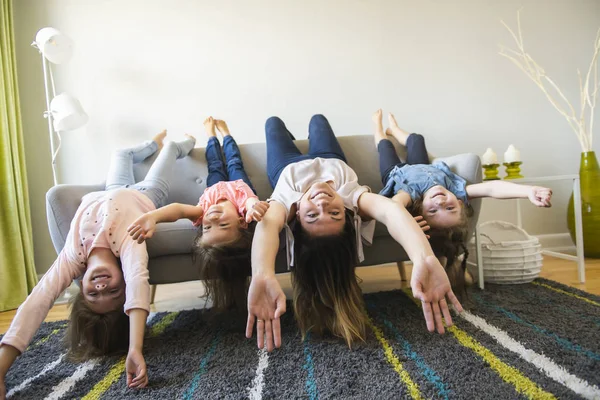 Mãe e filhas no sofá em casa de cabeça para baixo diversão no sofá — Fotografia de Stock