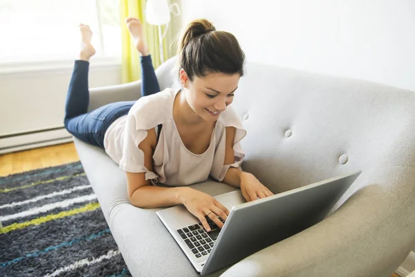 Vrouw met een laptop op de Bank thuis — Stockfoto