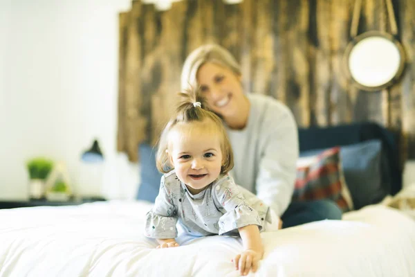 Mãe e sua filha bebê na cama se divertindo — Fotografia de Stock