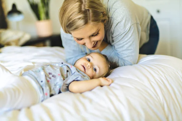 Madre y su hija bebé en la cama divirtiéndose — Foto de Stock