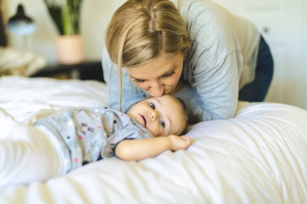 Madre y su hija bebé en la cama divirtiéndose — Foto de Stock