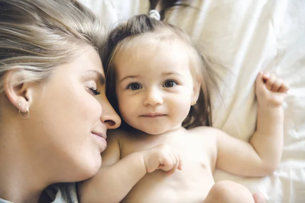 Madre y su hija bebé en la cama divirtiéndose — Foto de Stock