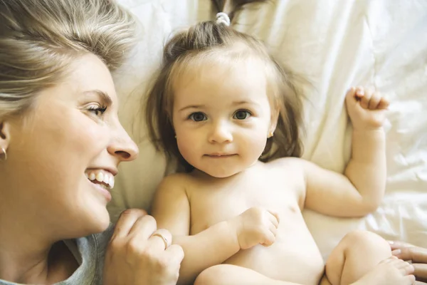 Madre y su hija bebé en la cama divirtiéndose — Foto de Stock