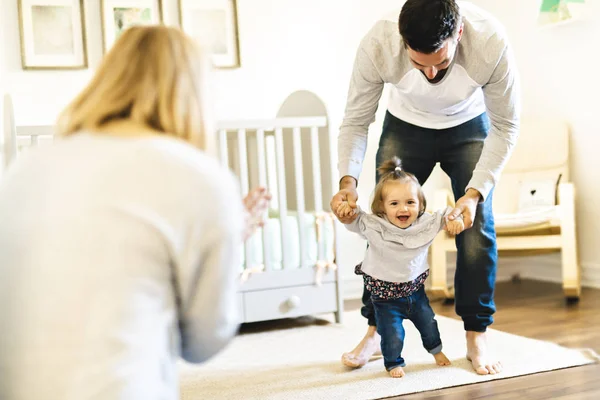 Niña pequeños primeros pasos con la ayuda de los padres — Foto de Stock