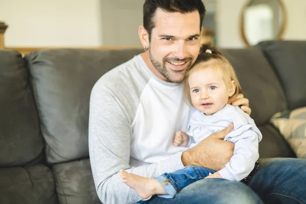 Padre joven con hija bebé en el sofá en casa — Foto de Stock