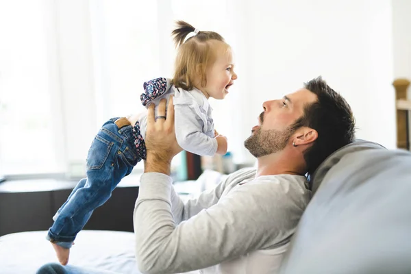 Giovane padre con bambina sul divano di casa — Foto Stock