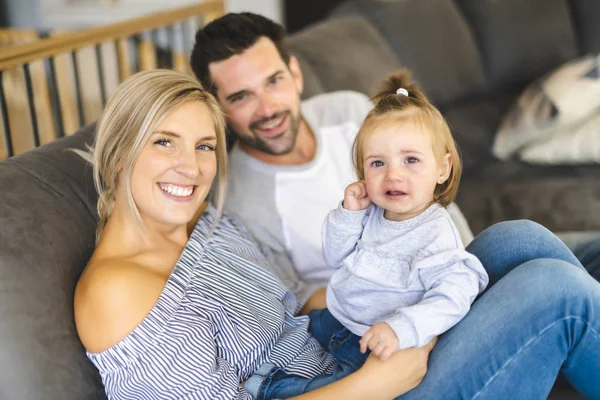 若い家族は泣いている赤ちゃんの自宅でソファの上の赤ちゃんの娘と — ストック写真