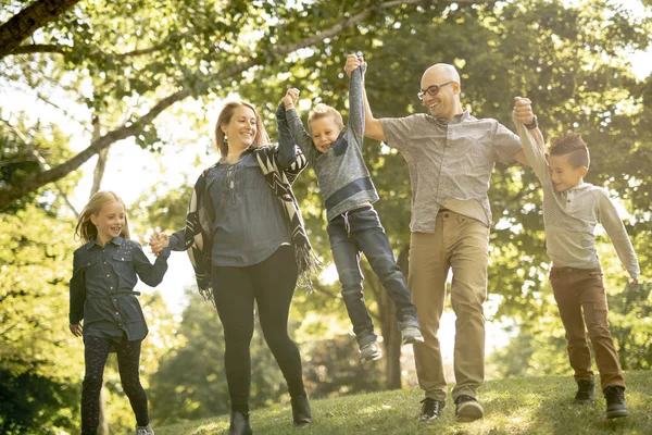 Una familia joven feliz afuera en la naturaleza verde — Foto de Stock