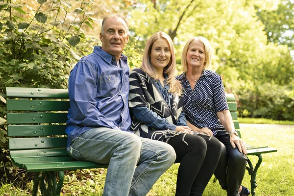 La familia se sienta en el banco la temporada otoñal — Foto de Stock