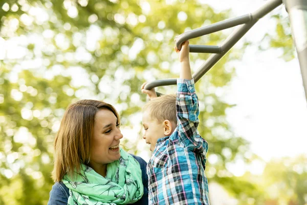 Un adorabile bambino che si gode il suo tempo in una struttura del parco giochi con la madre — Foto Stock