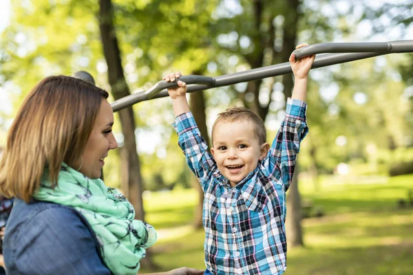 En bedårande liten pojke som njuter av sin tid i en lekplats struktur med mamma — Stockfoto