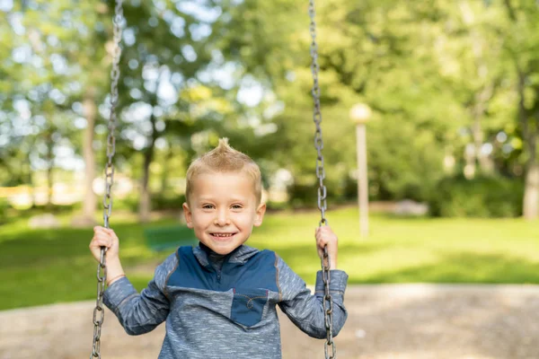 En pojke barn ha roligt på en gunga. — Stockfoto