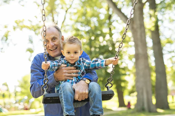 En farfar som driver hans sonson på rep swing — Stockfoto