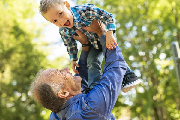 Großvater und kleiner Sohn amüsieren sich im Park — Stockfoto