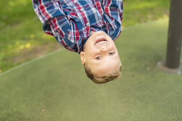 Un garçon mignon à l'envers sur une aire de jeux — Photo