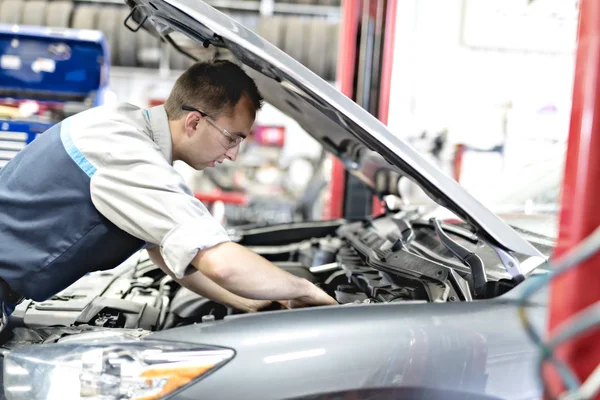 Knappe monteur baan in uniform werken op auto — Stockfoto