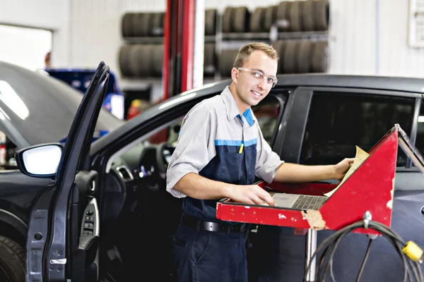 Knappe monteur baan in uniform werken op auto — Stockfoto