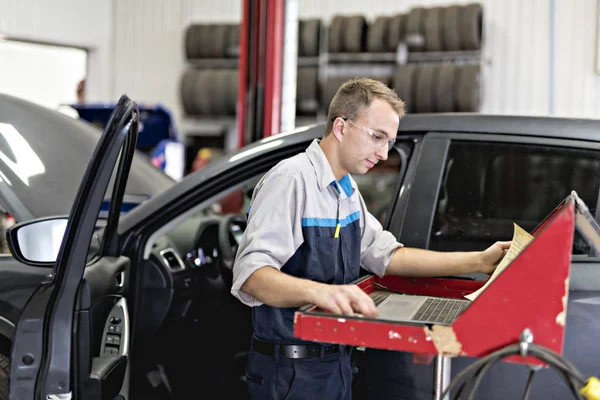 Knappe monteur baan in uniform werken op auto — Stockfoto