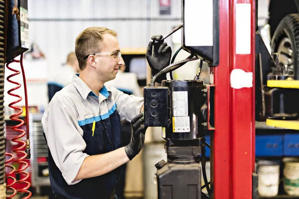 Knappe monteur baan in uniform werken op auto — Stockfoto