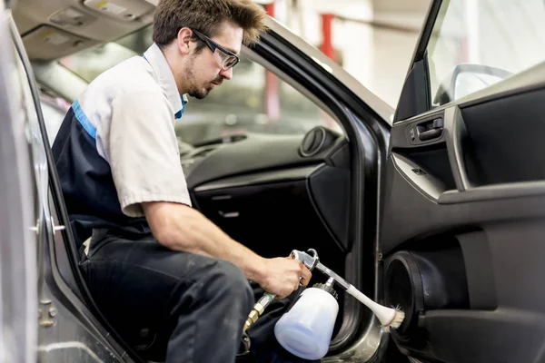 El hombre en el trabajo de limpieza dentro del automóvil en el lavado de coches — Foto de Stock