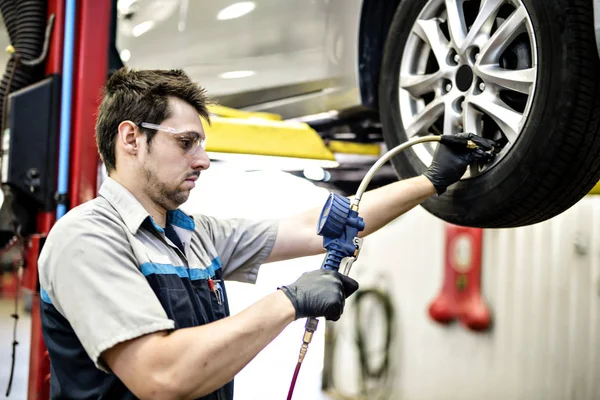 Trabajo mecánico guapo en uniforme trabajando en el coche — Foto de Stock